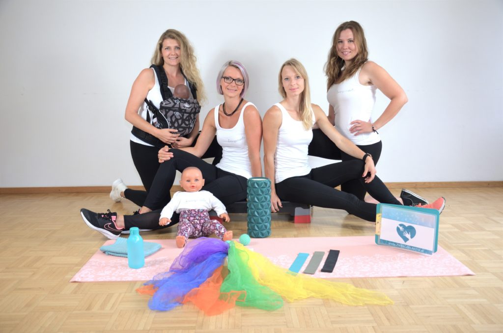 Auf dem Bild sieht man das Zwergerlaktiv Team mit Equipment (Faszienrolle, Tragepuppe, Stepper, Fitnessmatte und Terra-Bänder)